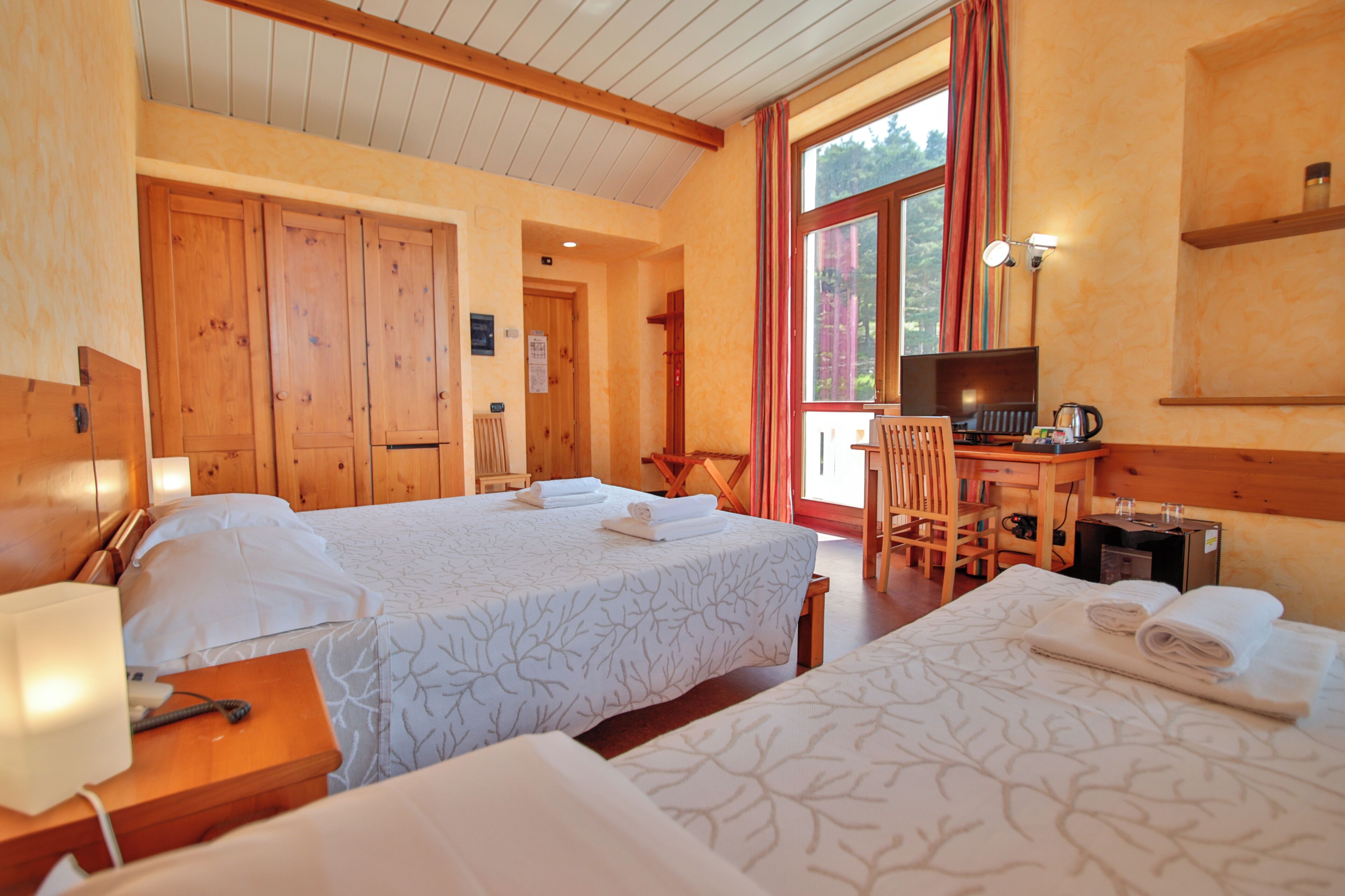 Habitación de hotel con dos camas, muebles de madera, un escritorio y una silla.
