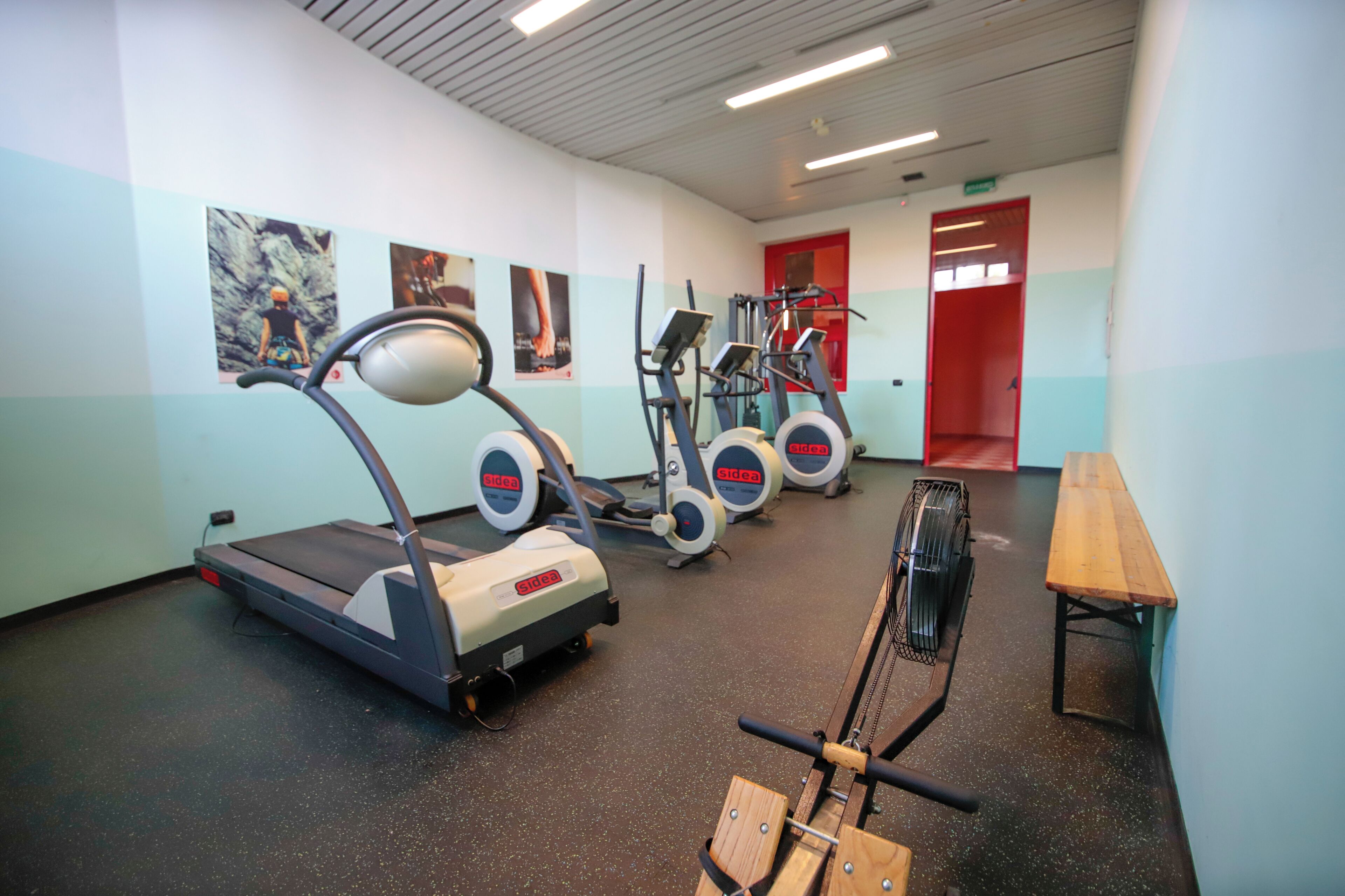 Un gimnasio con cintas de correr, elípticas y una máquina de remo.