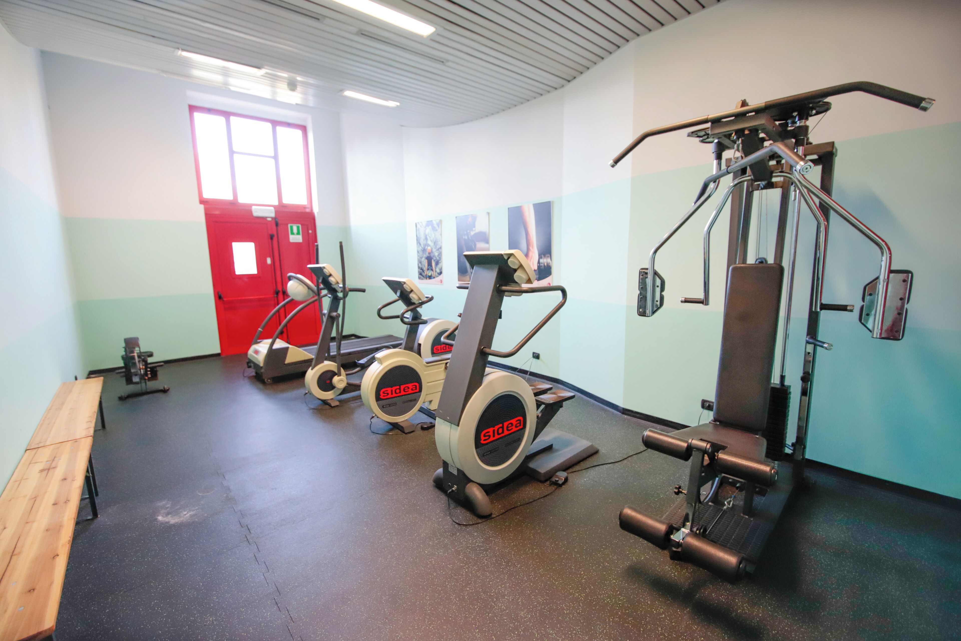 A gym with cardio machines, weightlifting equipment, and a bench.
