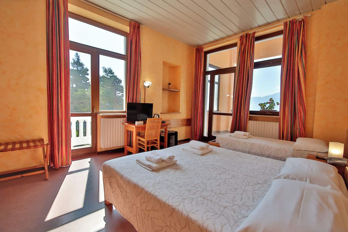 A hotel room with two beds, a desk, a chair, and a TV.