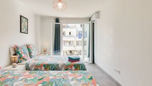 A bedroom with a bed, a nightstand, a lamp, and a view of the outside balcony.