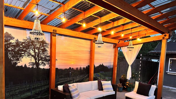 Une terrasse extérieure aménagée avec des meubles en osier, une table en bois et des guirlandes lumineuses.