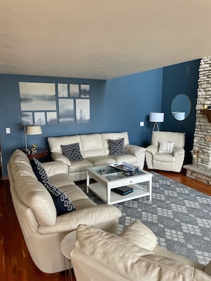 A living room with a beige sofa set, a coffee table, and a patterned rug.