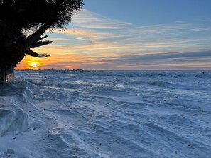 A snowy landscape with a sunset over a frozen body of water.