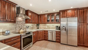 Una cocina moderna con armarios de madera, electrodomésticos de acero inoxidable y salpicadero de azulejos.