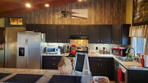 Una cocina moderna con armarios oscuros, un refrigerador de acero inoxidable, un microondas y una cafetera.