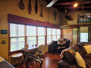 A dining area with a table, chairs, and a view through large windows. - Mountain view cabin, fully remodeled, huge screen in porch with panoramic view. (Franklin)