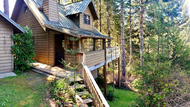 Una cabaña con terraza, rodeada de bosque.
