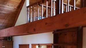 Un interior de madera con un entrepiso, un refrigerador y un conjunto de puertas de madera.
