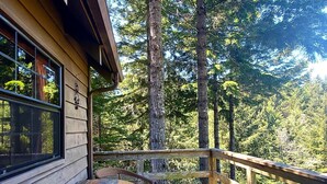Una terraza de madera con una mesa y sillas, con vistas a un área boscosa.