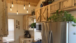 Eine moderne Küche mit Holdekor, Edelstahlgeräten und hängenden Pendelleuchten.