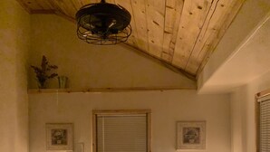 Ein Schlafzimmer mit Holzboden, einem Bett mit gestecktem Quilt, Nachttischlampen und einem Fenster mit Jalousien.