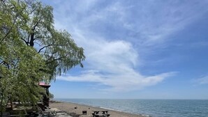 Een strand met een houten terras, een blauwe tafel en een zwarte stoel.