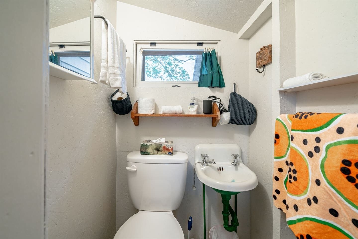 A compact bathroom with a toilet, sink, and window.