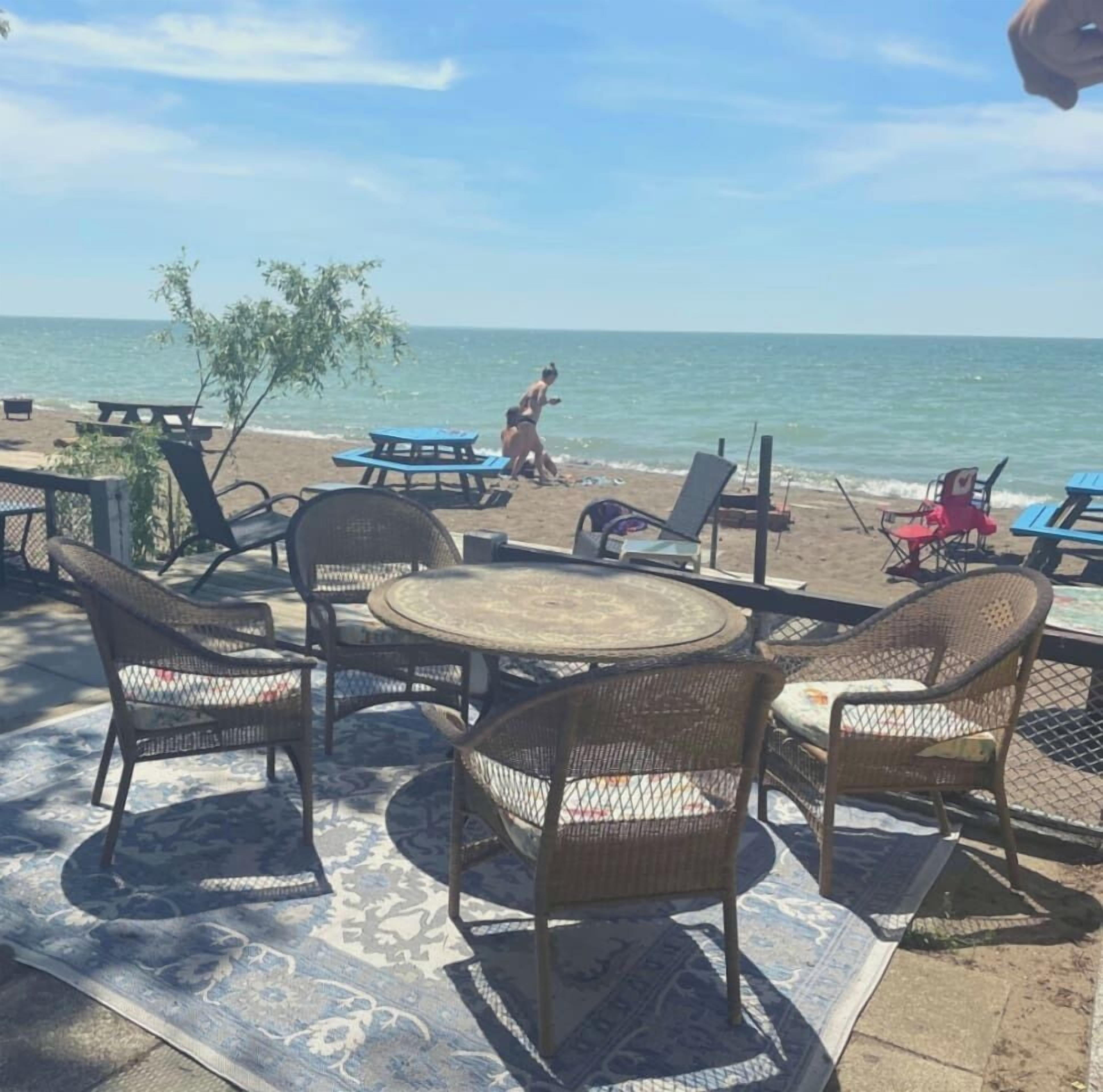 An outdoor seating area with wicker chairs and tables, overlooking a beach.