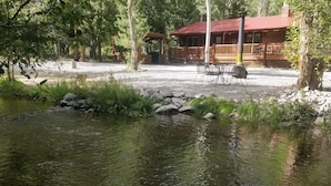 Eine Hütte mit rotem Dach, umgeben von Bäumen und einem kleinen Teich.