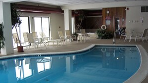 En indendørs swimmingpool med liggestole og borde hele vejen rundt.