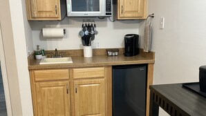 Eine kleine Küche mit Holzschränken, einer Mikrowelle, einer Kaffeemaschine und einem Geschirrspüler.