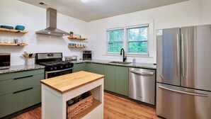 A modern kitchen with green cabinets, stainless steel appliances, and a wooden island. - Deacon Stays: The Brookwood - Walk to WFU (Winston-Salem)