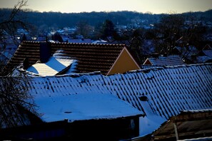 Vila coberta de neve com casas tradicionais e um campanário de igreja imponente.