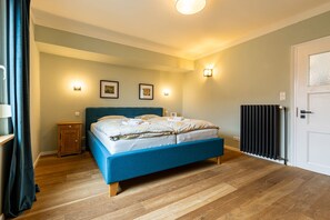 Quarto com cama, mesa de cabeceira, radiador e luminárias fixadas na parede.