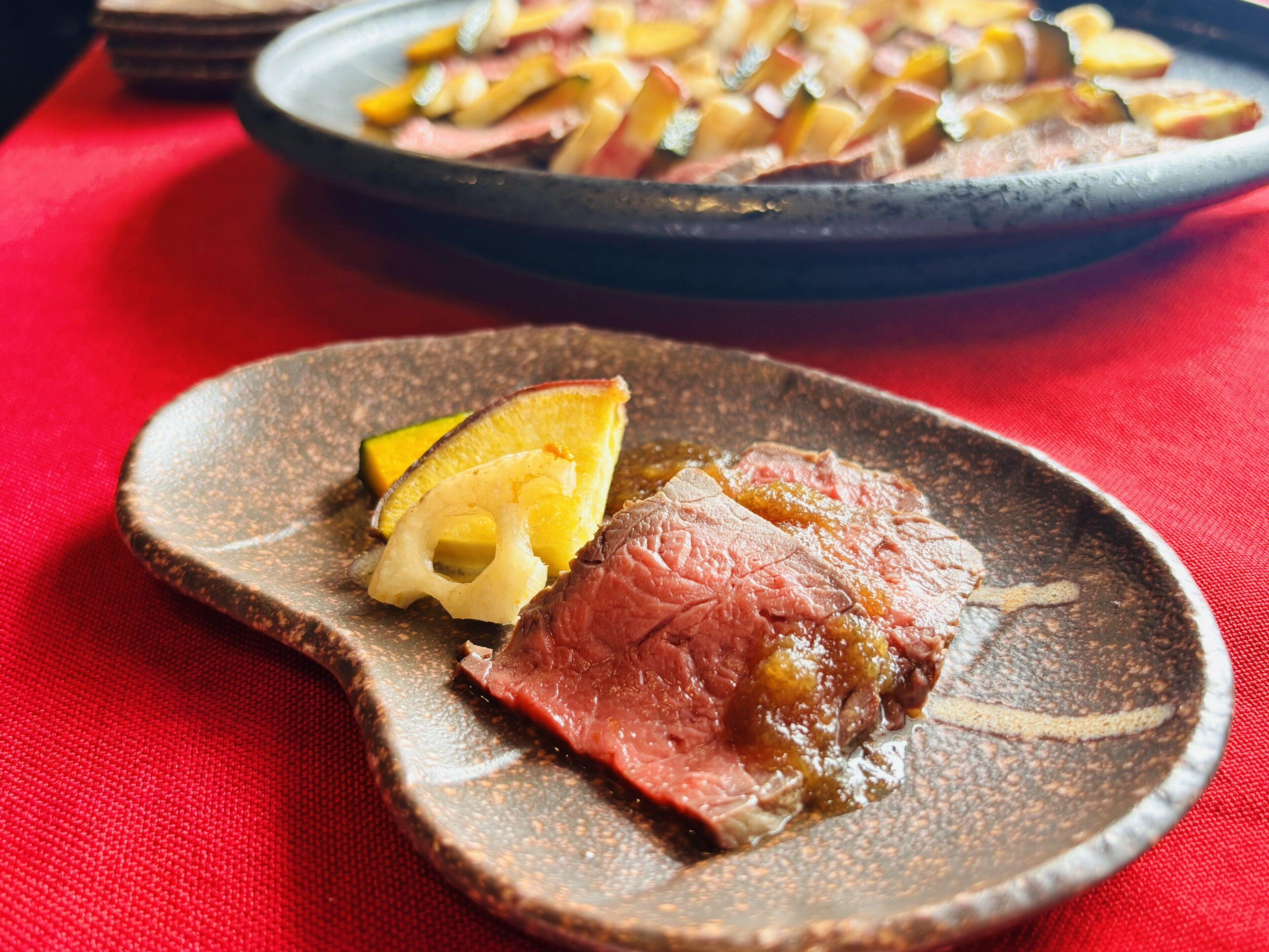 A plate of food with a slice of meat and a wedge of pineapple on a textured plate.