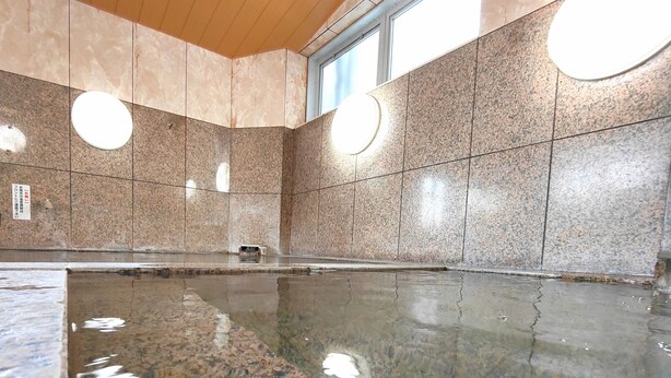 A large indoor swimming pool with a polished granite floor, surrounded by walls with a speckled pattern. - Saga City Hotel (Saga)