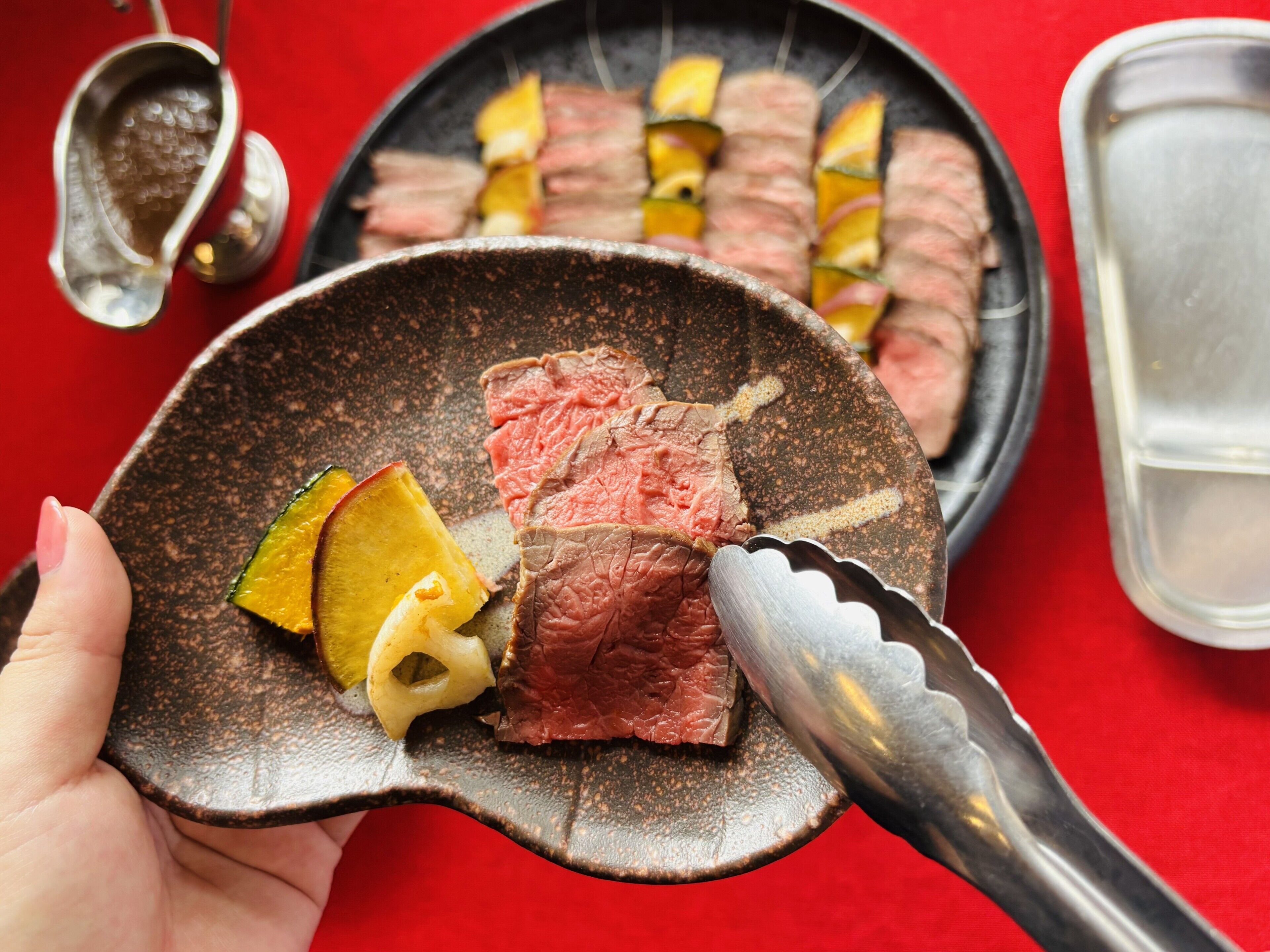 Una persona sosteniendo un plato de cerámica con carne y verduras en porciones.