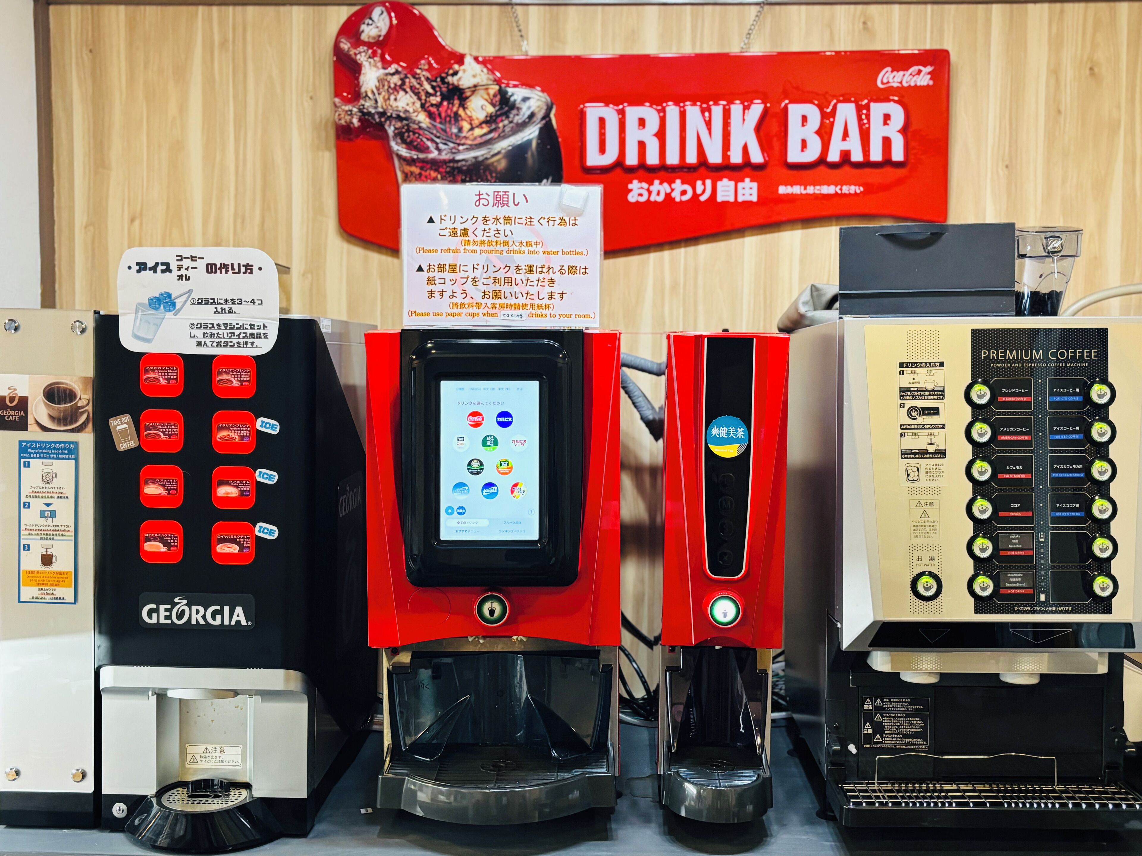 A coffee machine with a touchscreen interface, a drink bar sign, and a premium coffee machine.