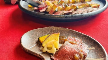 A plate of food with meat and vegetables on a red tablecloth.
