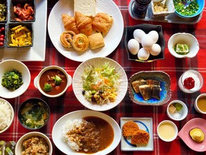 A variety of dishes including rice, soup, and bread, arranged on a red and black checkered tablecloth.
