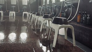 A wet floor in a public restroom with mirrors and toiletries. - Saga City Hotel (Saga)