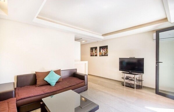 Relax in this stylish living room with a sofa, flat-screen TV, and door leading to another room.