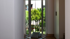 A modern interior with a sliding glass door leading to a garden with potted plants and a tree.