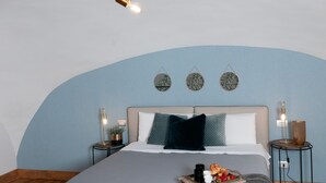 A modern bedroom with a central bed, bedside tables, a unique ceiling light fixture, and decorative wall art.