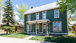 A two-story house with a porch, a front door, and a mailbox.