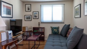 A living room with a grey sofa, a wooden coffee table, a bookshelf, and a television.