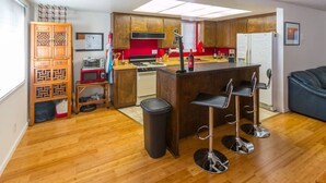 A compact kitchen with wooden cabinets, a central island with bar stools, a gas stove, and a refrigerator.