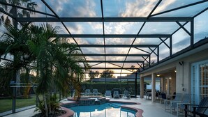 Una piscina con techo de vidrio, rodeada de palmeras y sillas de descanso.