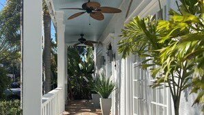 Une allée couverte dotée d’un sol carrelé, de ventilateurs de plafond et de plantes en pot.