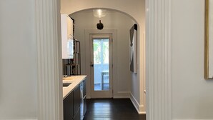 Un couloir avec un plancher en bois foncé, des murs blancs et une porte blanche au fond.