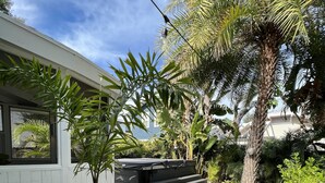 Un jardin résidentiel avec un chemin pavé, des palmiers et un petit escalier menant à une terrasse.