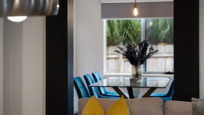 Un comedor moderno con una mesa de vidrio, sillas azules y un jarrón de flores.