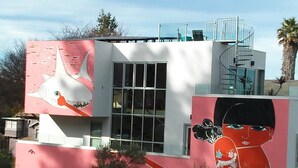 Un edificio moderno con fachada rosa, grandes ventanales y una escalera de caracol.