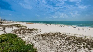 A beach with white sand, clear blue sky, and ocean.