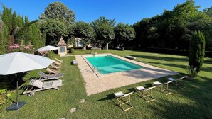 A backyard with a swimming pool, lounge chairs, and a small gazebo. - Villa Tourterelle (Caussade)
