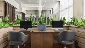 A modern office space with two desks, each with a computer and keyboard, flanked by two office chairs. - Embassy Suites by Hilton Round Rock (Round Rock)