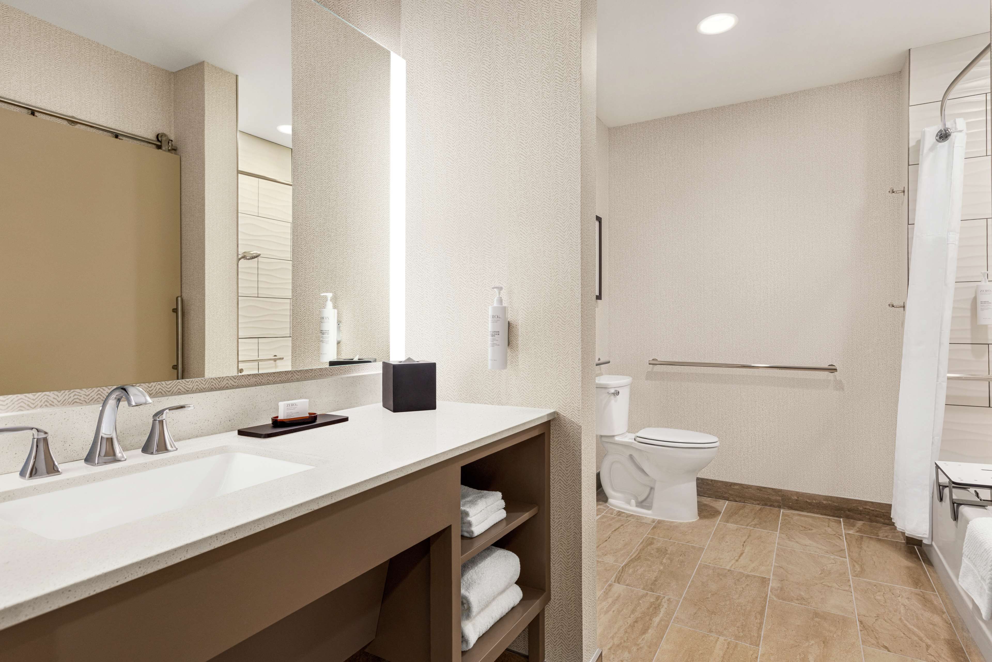 Un baño moderno con un espejo grande, dos lavamanos, un inodoro y una zona de ducha.