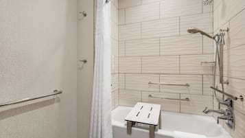 A modern bathroom with a shower, a bathtub with a small stool, and a towel rack.