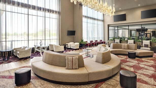 A spacious lobby with a large curved sofa, multiple seating options, and a modern chandelier. - Embassy Suites by Hilton Round Rock (Round Rock)